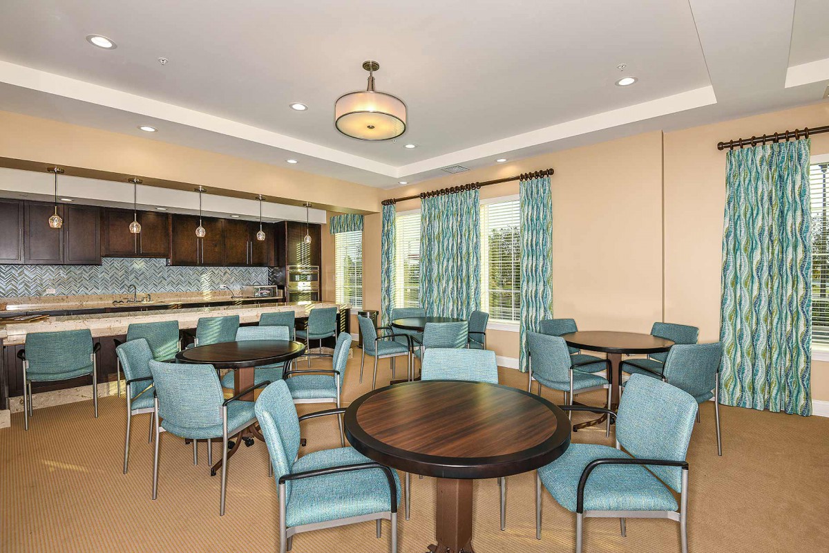A modern dining area with blue chairs and round tables, featuring large windows and contemporary lighting.
