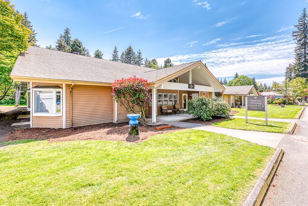 A single-story house with a well-maintained front lawn and shrubs on a sunny day.