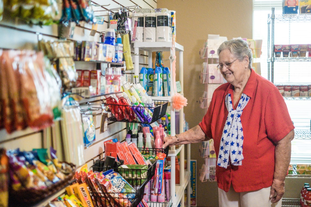 An elderly woman shopping in a grocery store aisle.