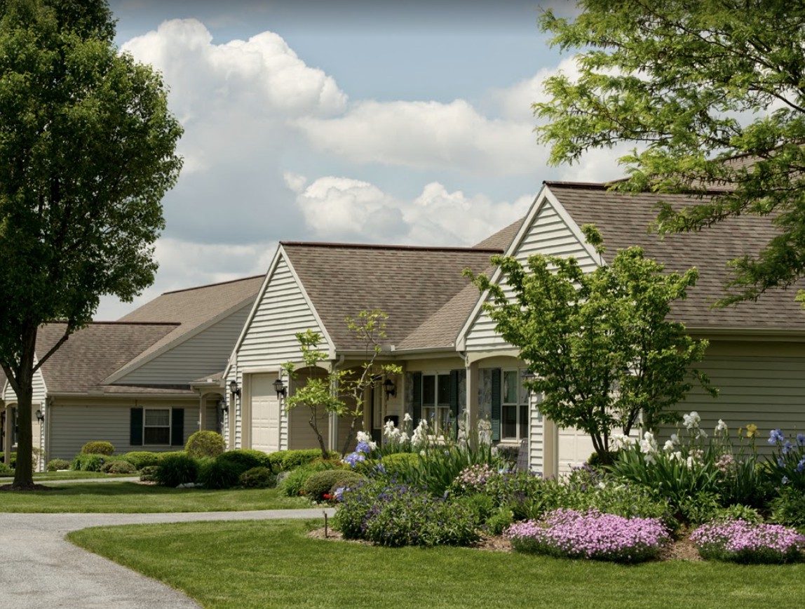 A suburban house with a well-maintained garden and vibrant landscaping under a partly cloudy sky.