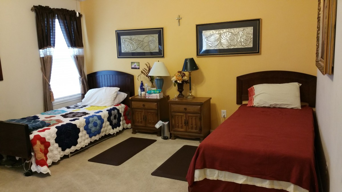 A cozy bedroom with two twin beds, each accompanied by a nightstand and lamp, featuring decorative mirrors on the wall.