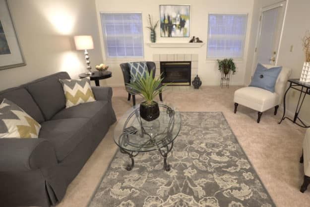 A cozy living room with modern decor, featuring a sofa, coffee table, and a decorative fireplace.