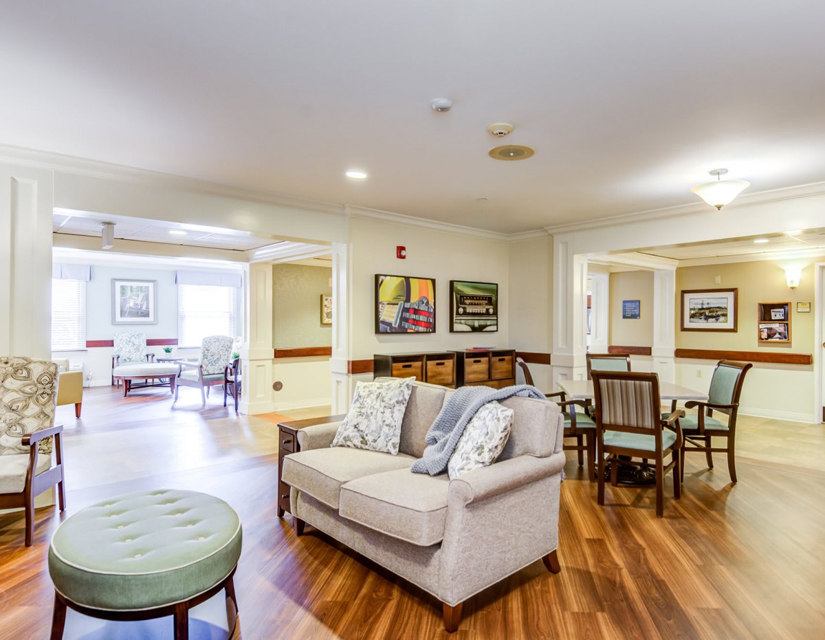 A cozy living room with a sofa and dining area, featuring wooden flooring and decorative artwork.