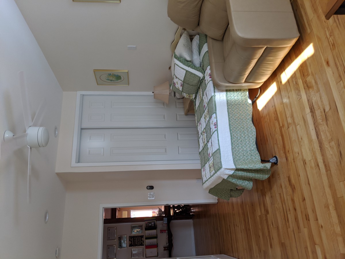 A cozy living room featuring a beige couch and wooden flooring, illuminated by natural sunlight.