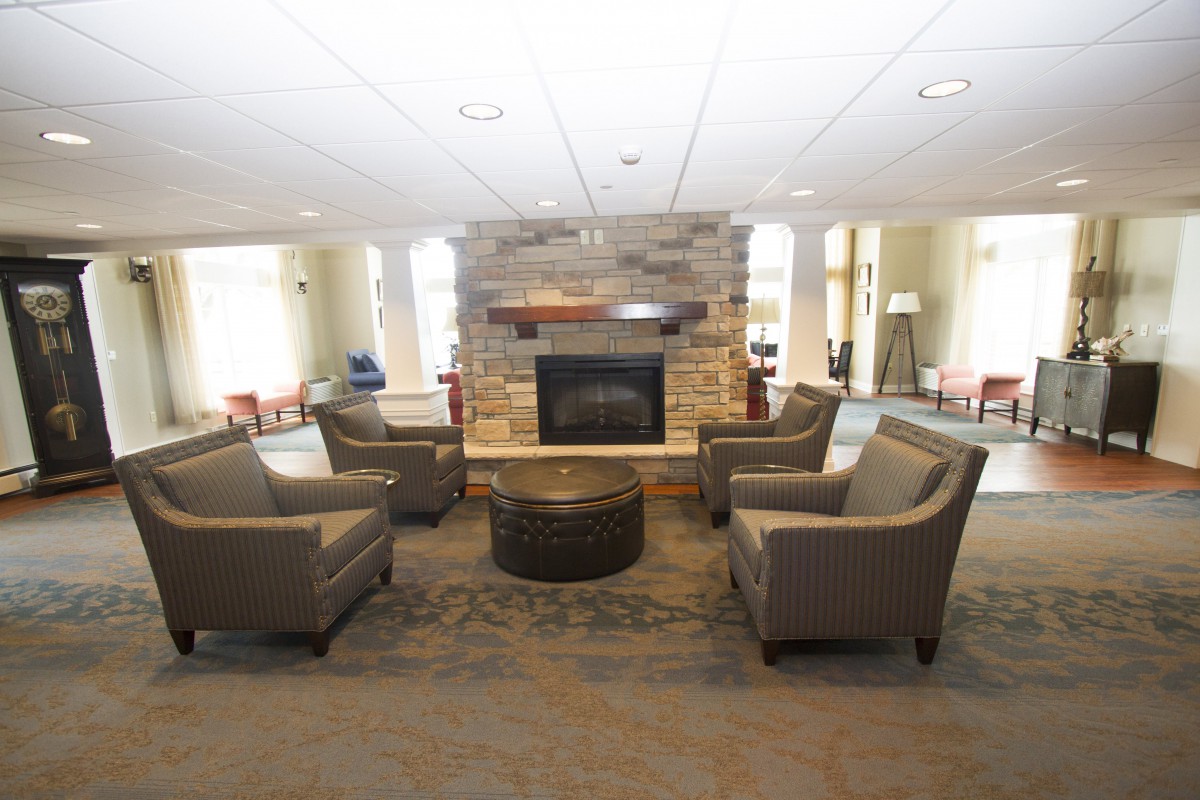 A modern lobby area with comfortable seating surrounding a central fireplace.