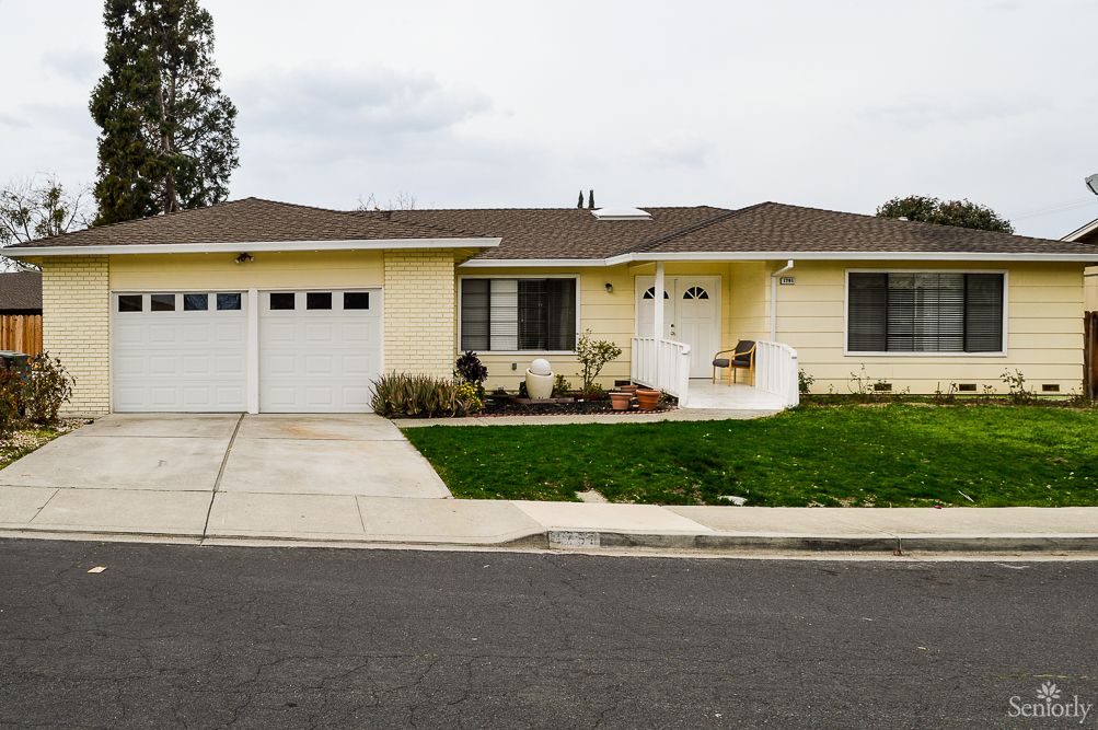 A suburban yellow house with a garage and a small front yard.