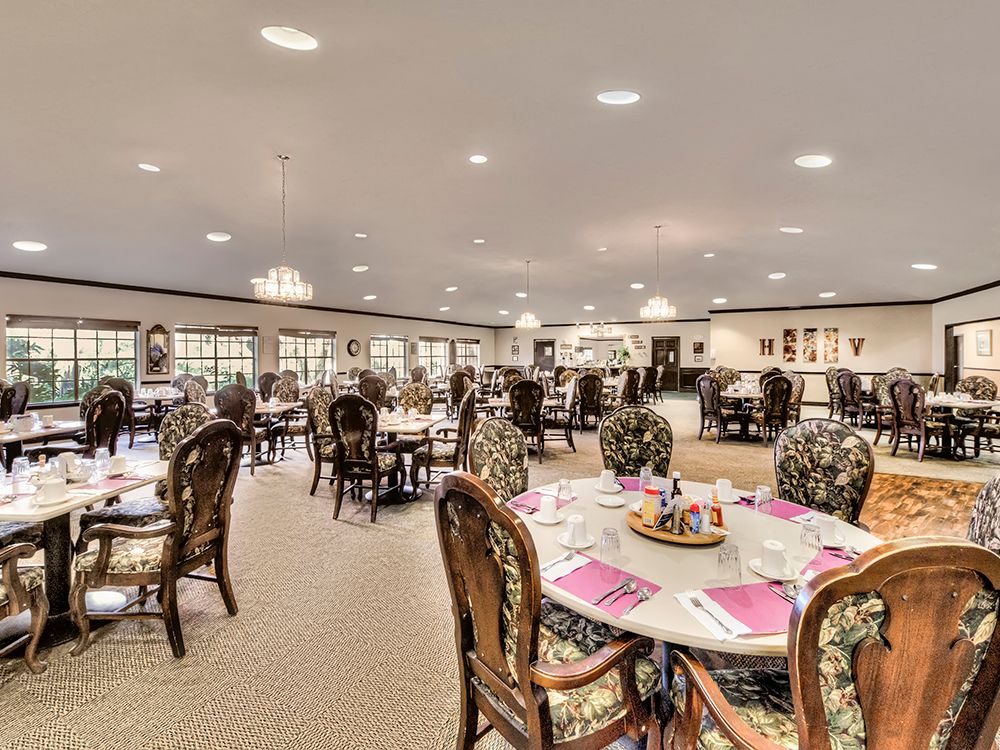 An elegant dining room with multiple tables and chairs, well-lit and decorated.