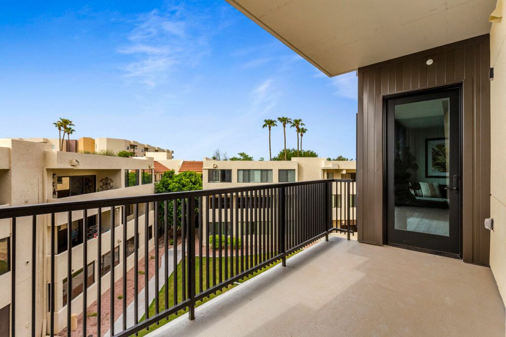 A modern apartment balcony with a view of surrounding buildings and palm trees.