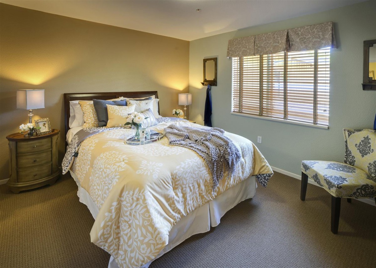 A cozy bedroom with a neatly made bed, soft lighting, and neutral color tones.
