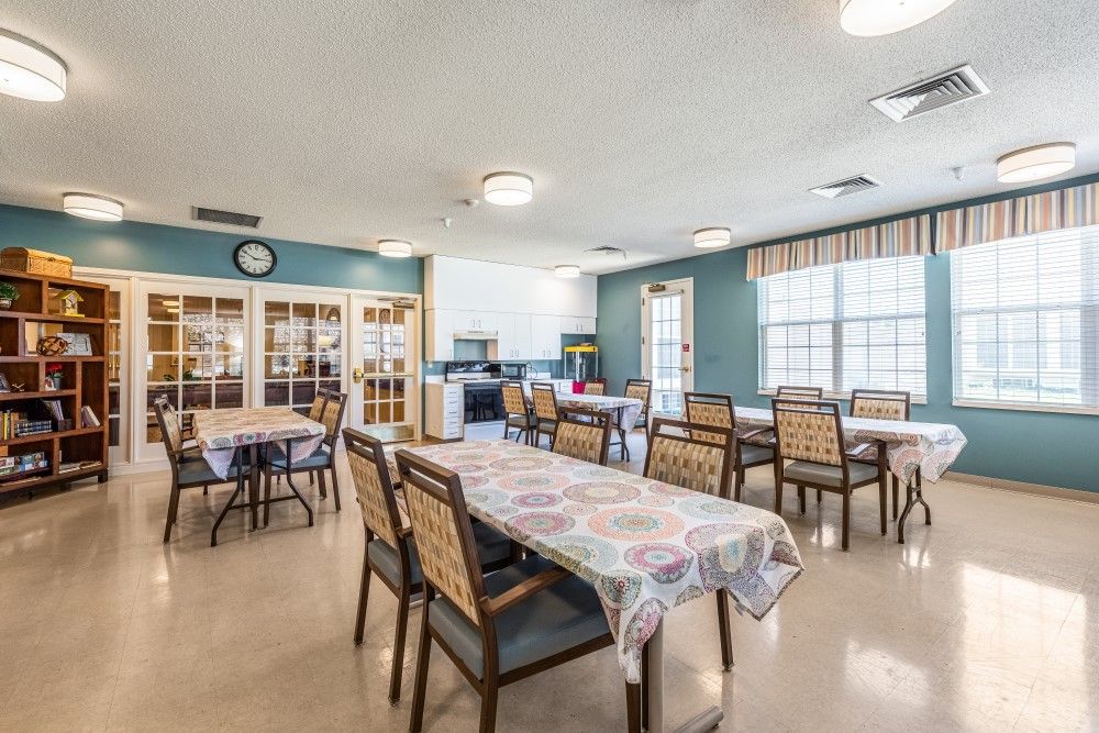 A spacious dining area with tables and chairs, featuring large windows letting in natural light.