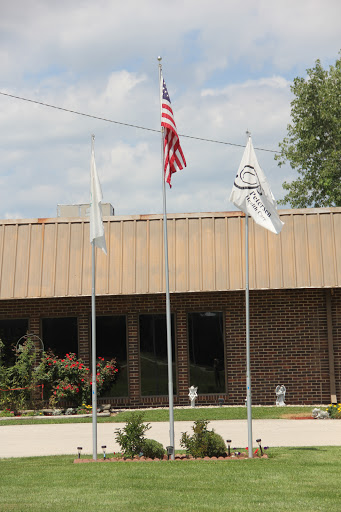 A view of a building with the American flag and two other flags flying in front.