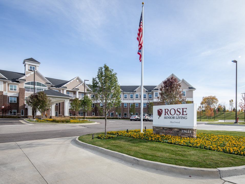 A view of the main entrance of a college campus with an American flag and signage in front.