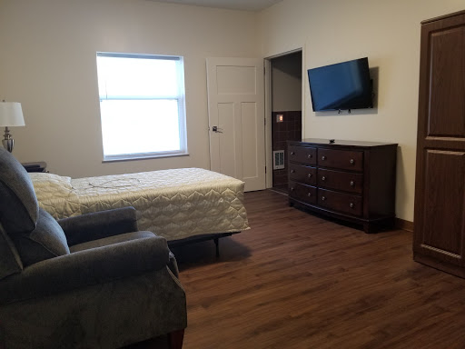 A cozy bedroom featuring a television, dresser, and comfortable furniture.
