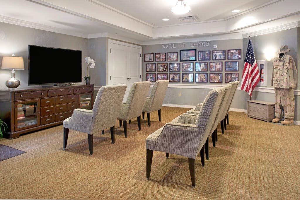 A cozy home theater setup with rows of plush seating, a large television, and framed photos on the wall.