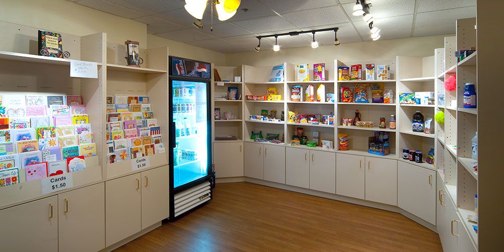 A well-organized retail store with shelves stocked with various products and a refrigerator.