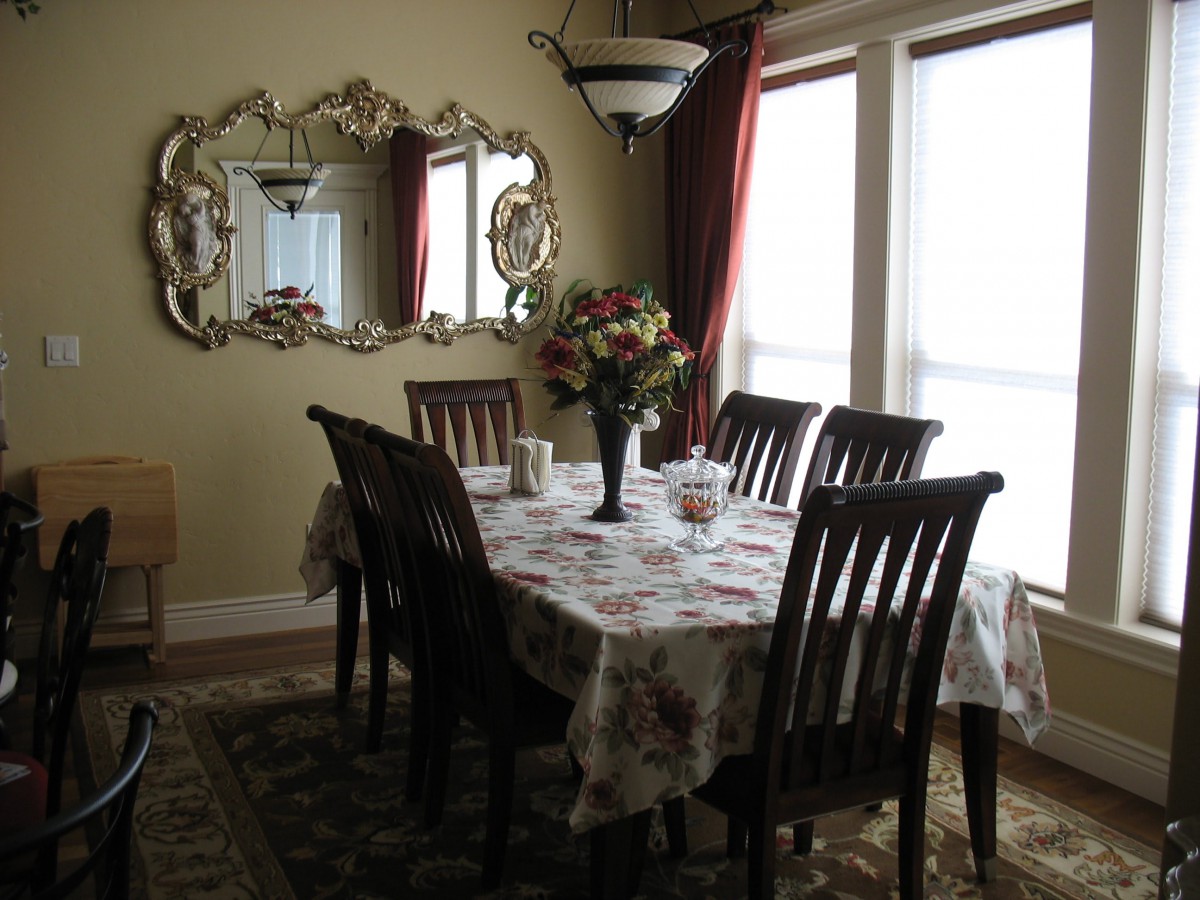 A cozy dining room with a table set for six, adorned with a floral centerpiece and surrounded by elegant decor.