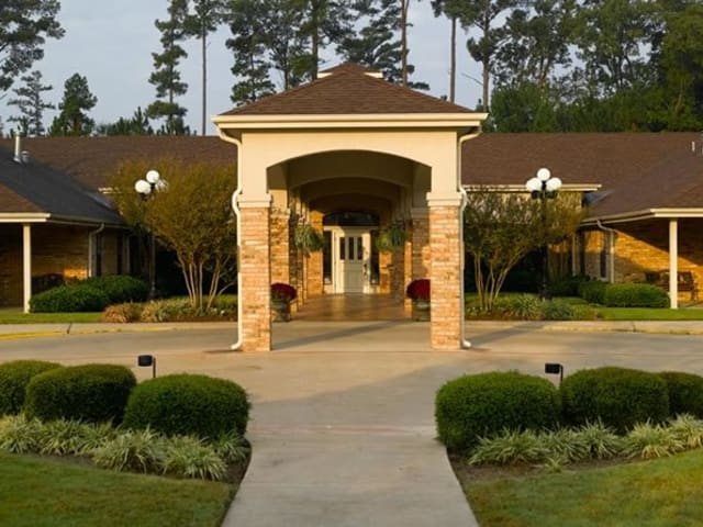 A beautifully designed building entrance with a covered pathway and surrounding greenery.