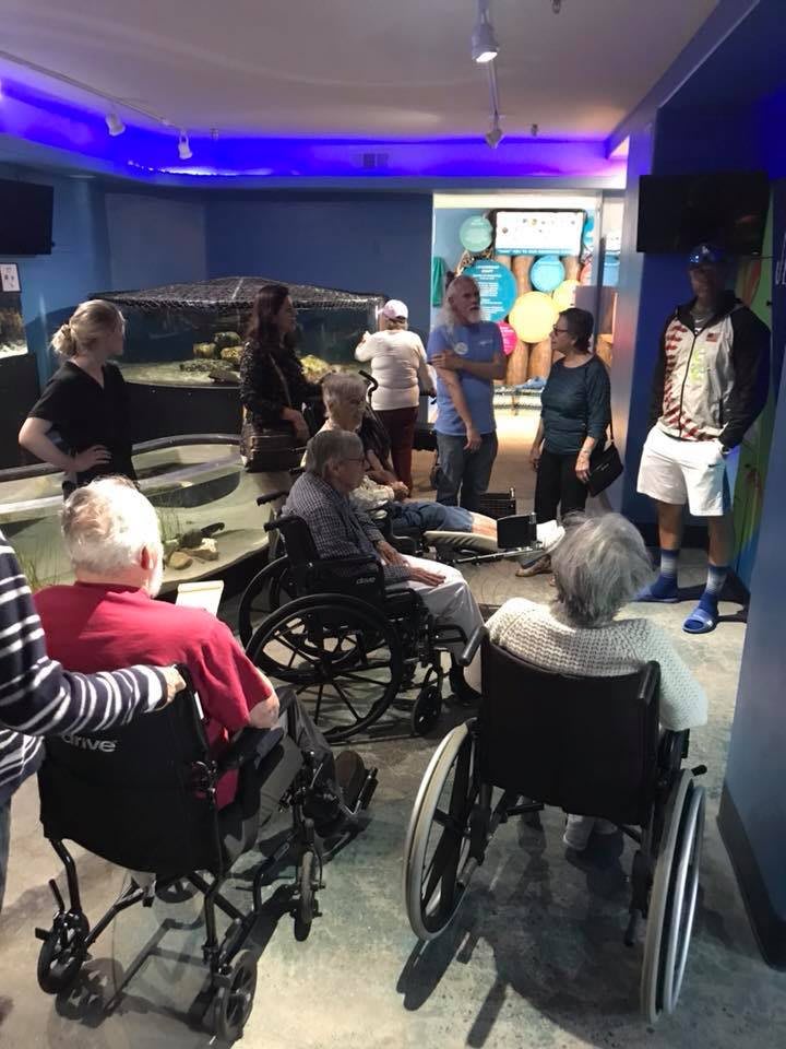 A group of people, some in wheelchairs, gathered indoors for a meeting.