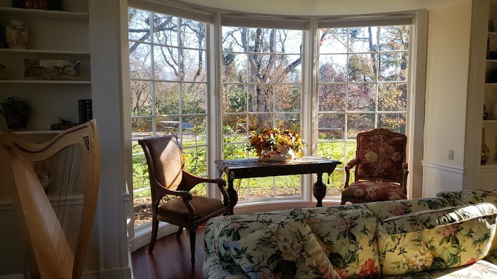 A cozy room with a large window, featuring two chairs and a table bathed in sunlight.