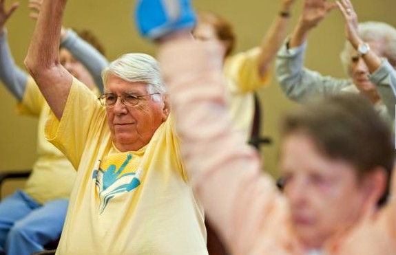 A group of senior citizens participating in a fitness class, engaging in an exercise routine.