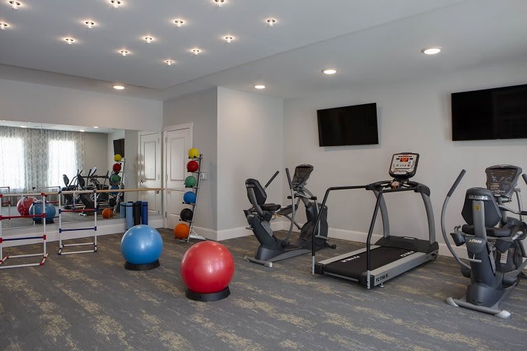 A modern gym with various fitness equipment including a treadmill, exercise bike, and exercise balls.