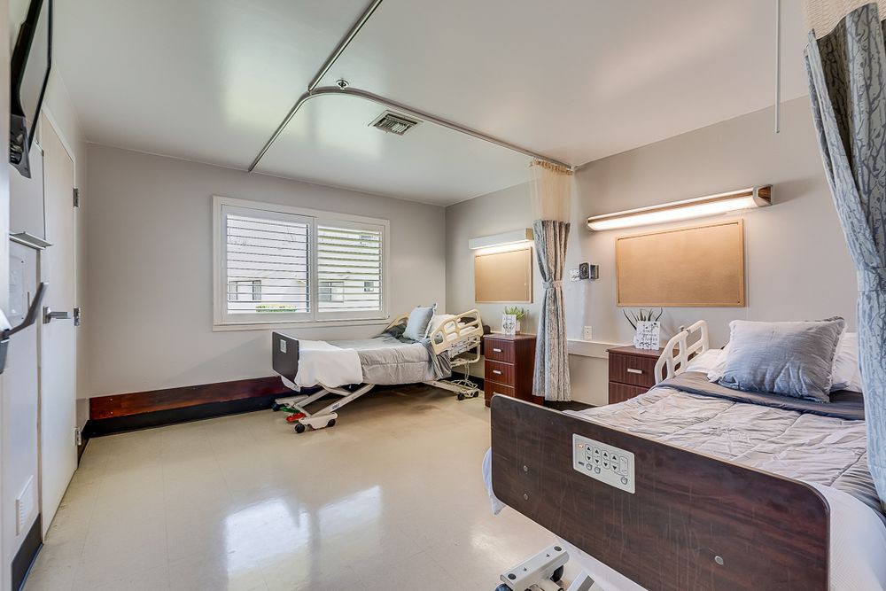 A clean and empty hospital room with two patient beds and medical equipment.