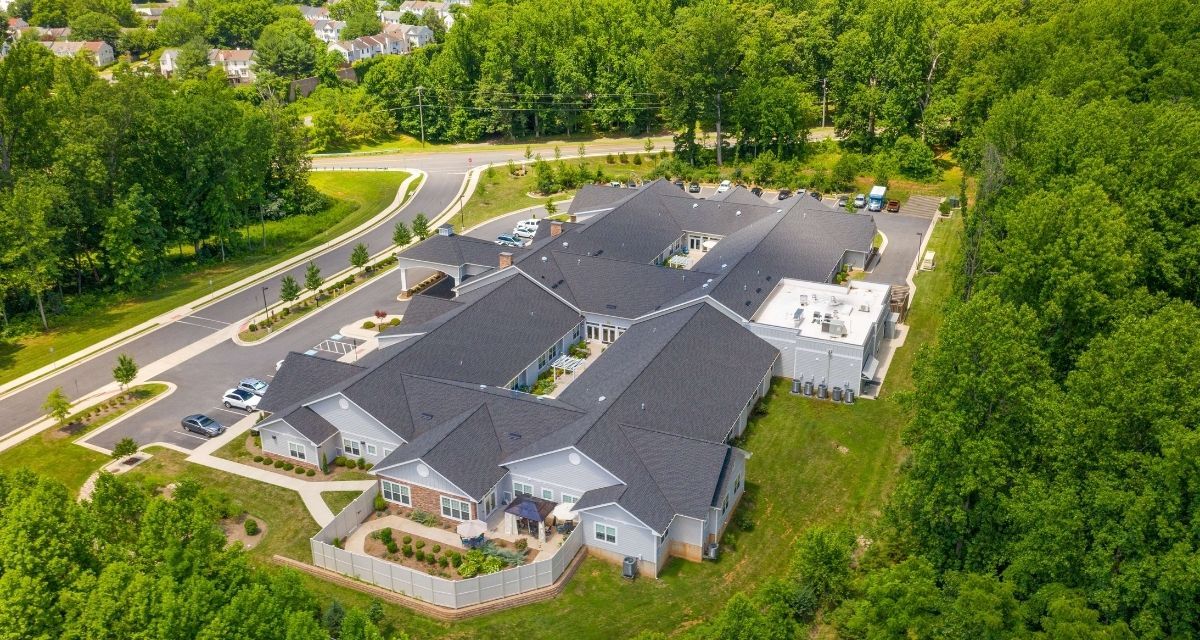 Aerial view of a large building complex surrounded by greenery and roads.