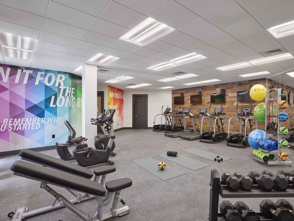A modern gym featuring treadmills, dumbbells, and other exercise equipment in a spacious workout area.