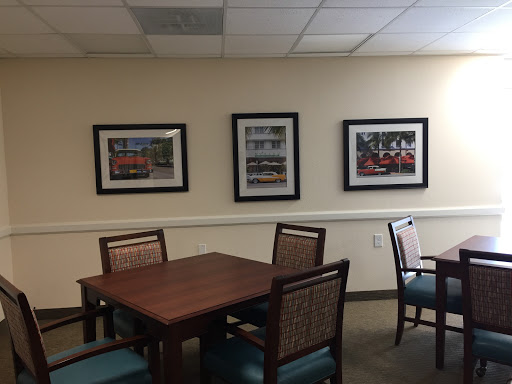A cozy meeting room featuring a wooden table, chairs, and framed artwork on the walls.