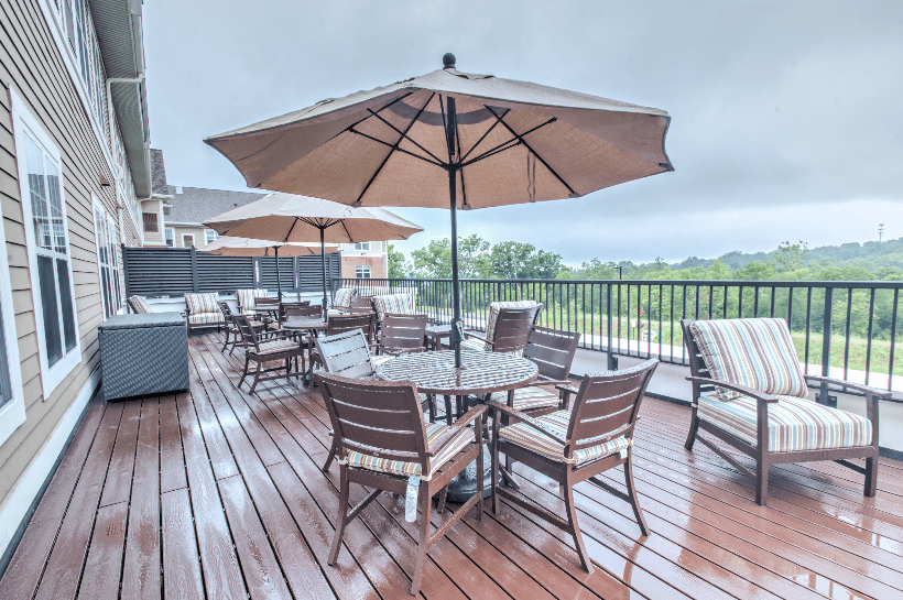 A spacious outdoor patio featuring several tables with umbrellas and chairs on a wooden deck.