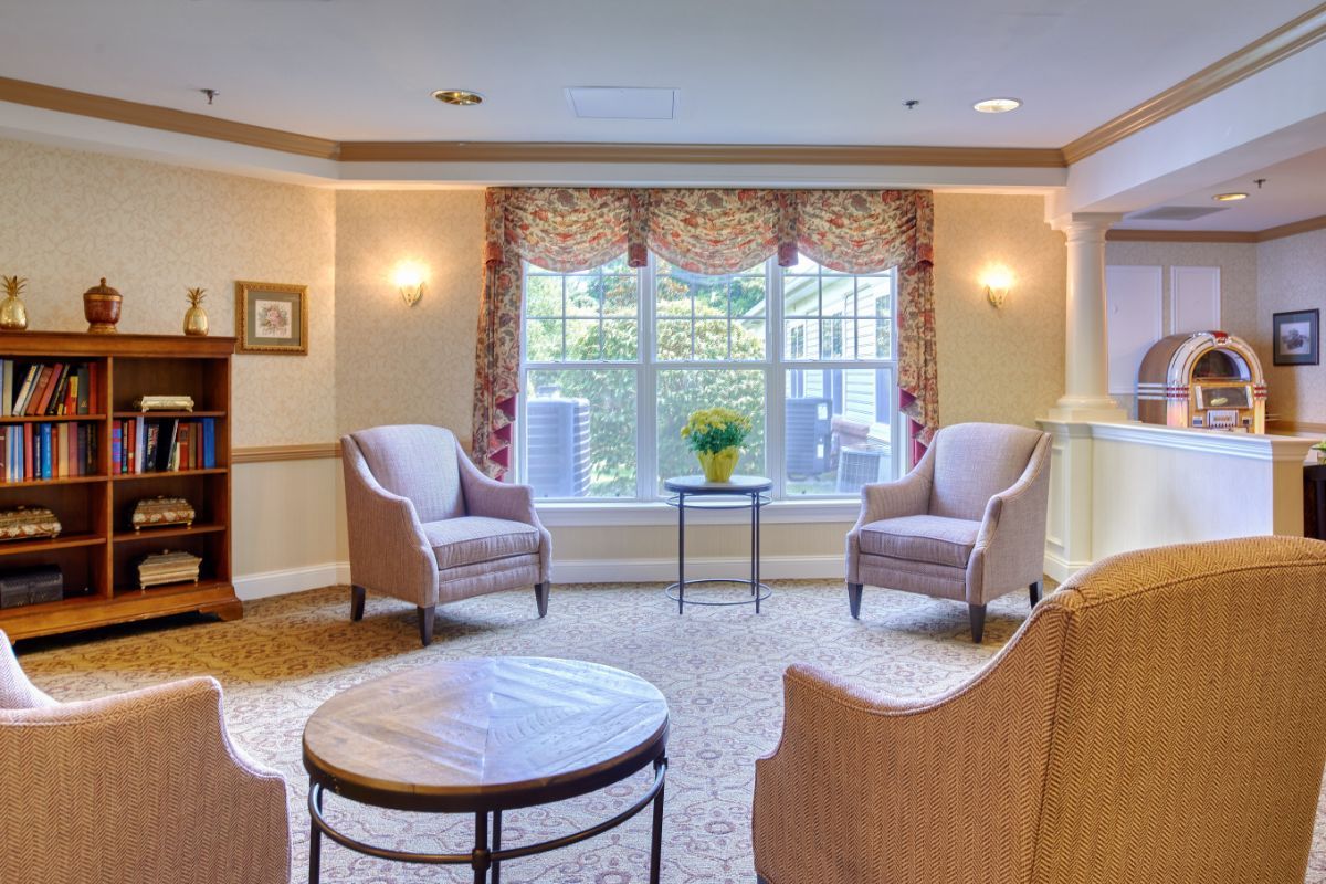 A cozy living room with two armchairs, a small table, and a large window.