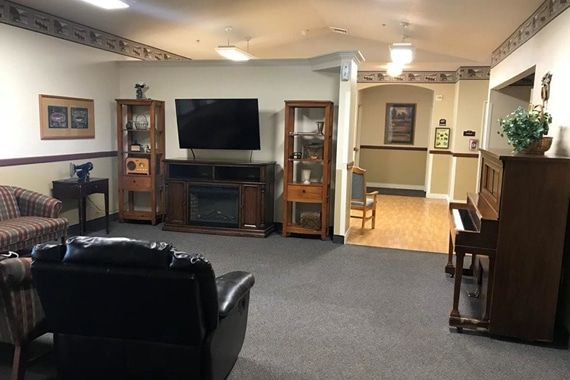 A cozy living room with a flat-screen TV, cabinets, and comfortable seating.