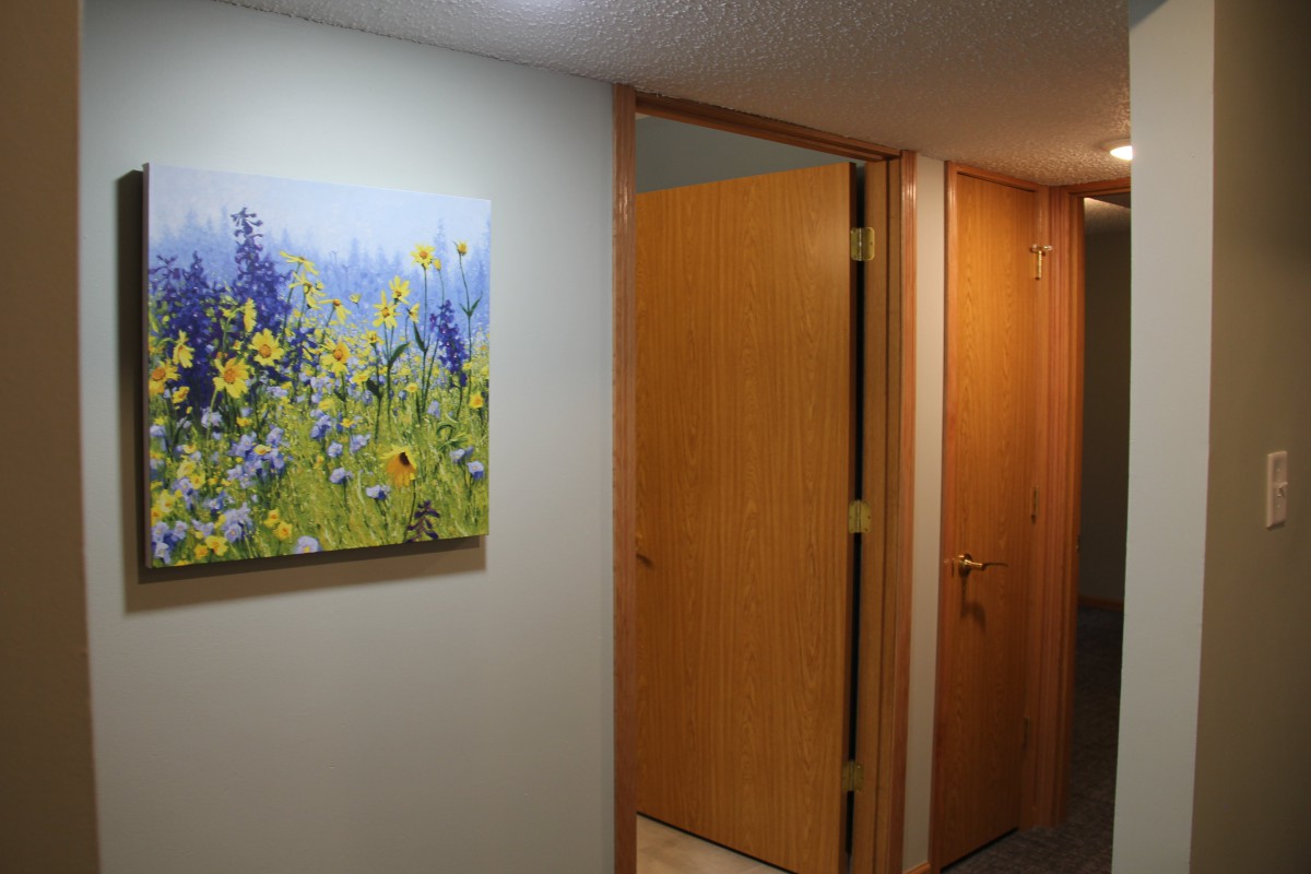 A hallway featuring closed wooden doors and a colorful floral painting on the wall.