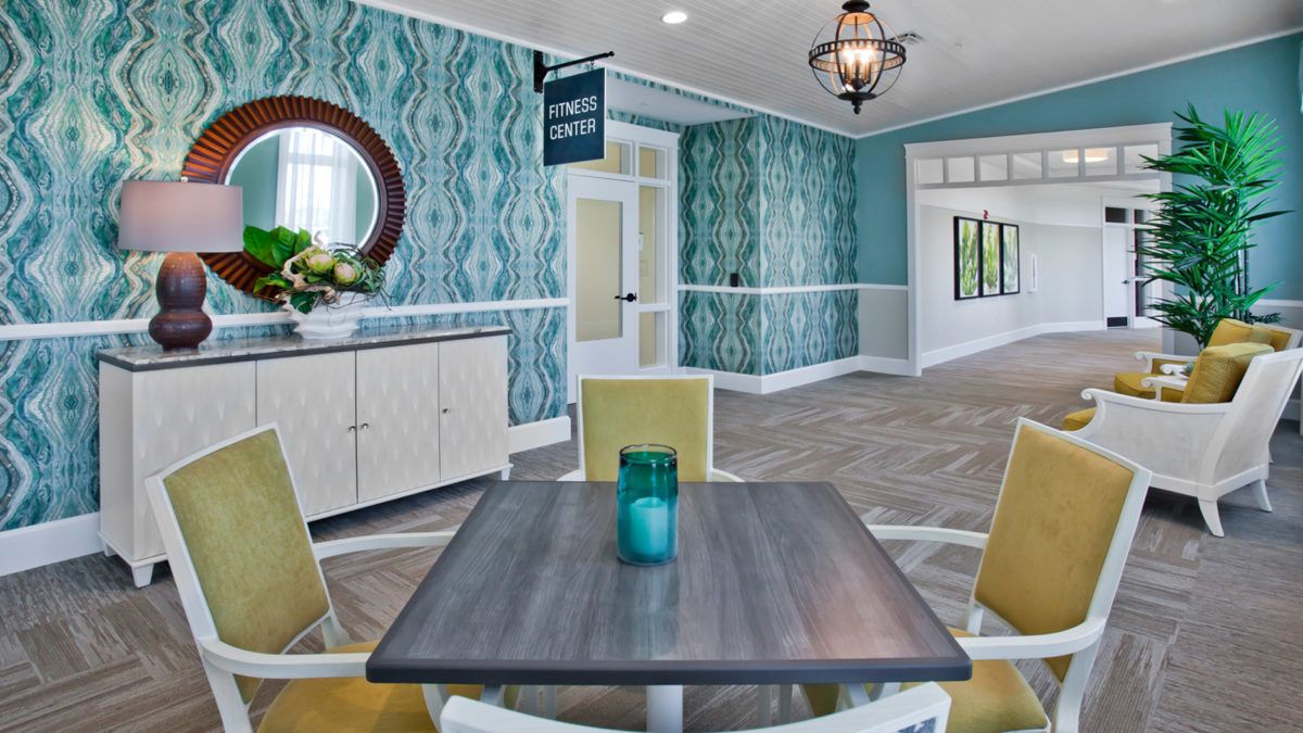 A stylish lobby area featuring a table with chairs, modern decor, and a decorative chandelier.