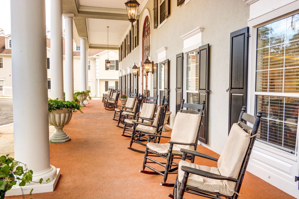 A picturesque porch lined with rocking chairs and elegant columns.