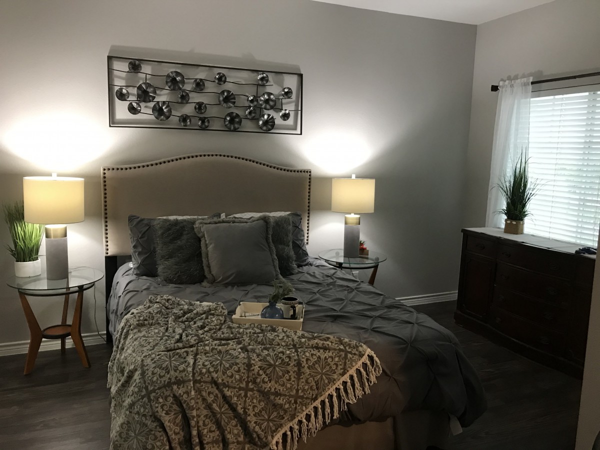 A cozy bedroom featuring a bed with multiple pillows, two lit lamps on nightstands, and decorative wall art.