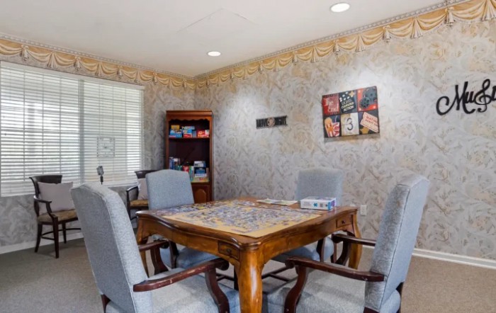 A small conference room with a wooden table and upholstered chairs, decorated with artwork on the walls.