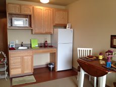 A small kitchen and dining area with basic appliances and wooden furniture.