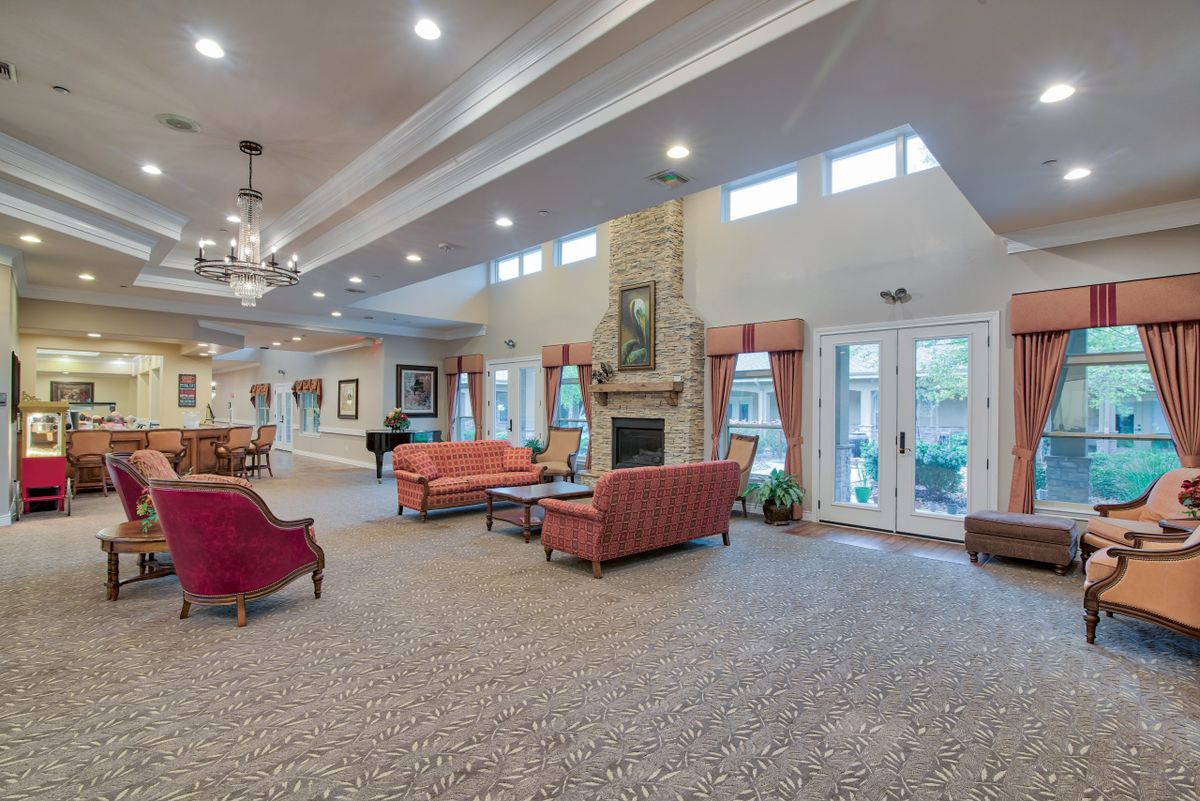 A spacious and elegantly decorated living room featuring comfortable sofas, a central fireplace, and large windows for natural light.