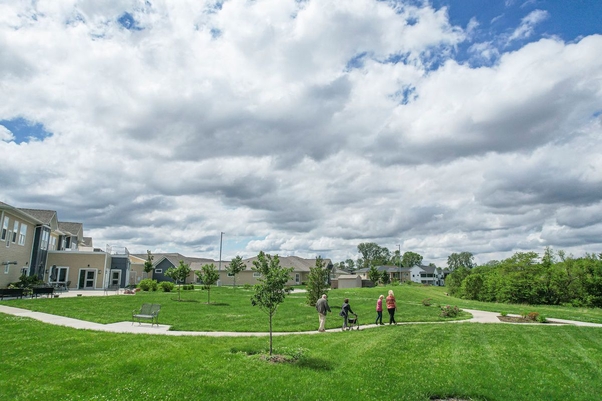 A scenic view of a park with people walking on a cloudy day.