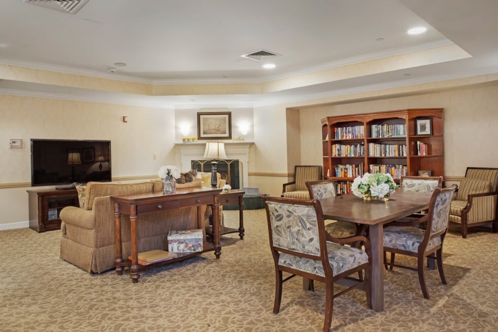 A cozy living room area featuring a library with bookshelves, comfortable seating, and a table with chairs.