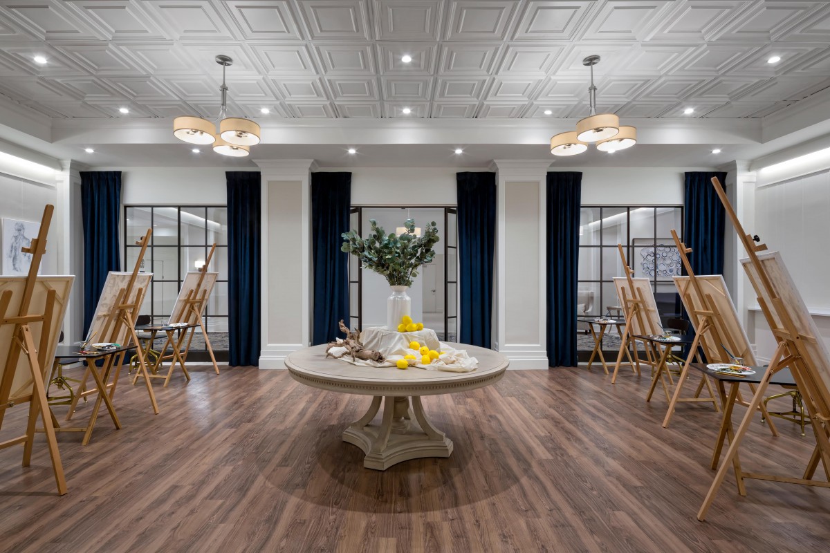 An elegantly designed event space featuring a central round table adorned with flowers, surrounded by sophisticated lighting and decor.