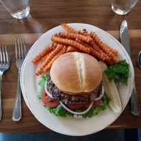 A delicious burger meal with sweet potato fries and a pickle.