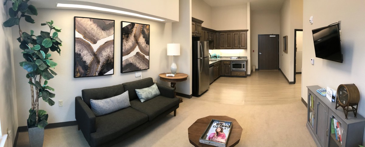 A modern apartment with an open living room and kitchen layout, featuring stylish furniture and artwork.