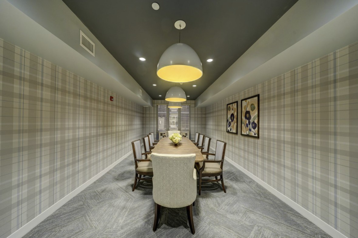 A modern dining or conference room featuring a long table with chairs and decorative pendant lighting.