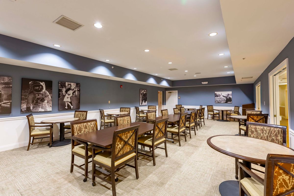 A spacious dining area with multiple tables and chairs, decorated with artwork on blue-painted walls.