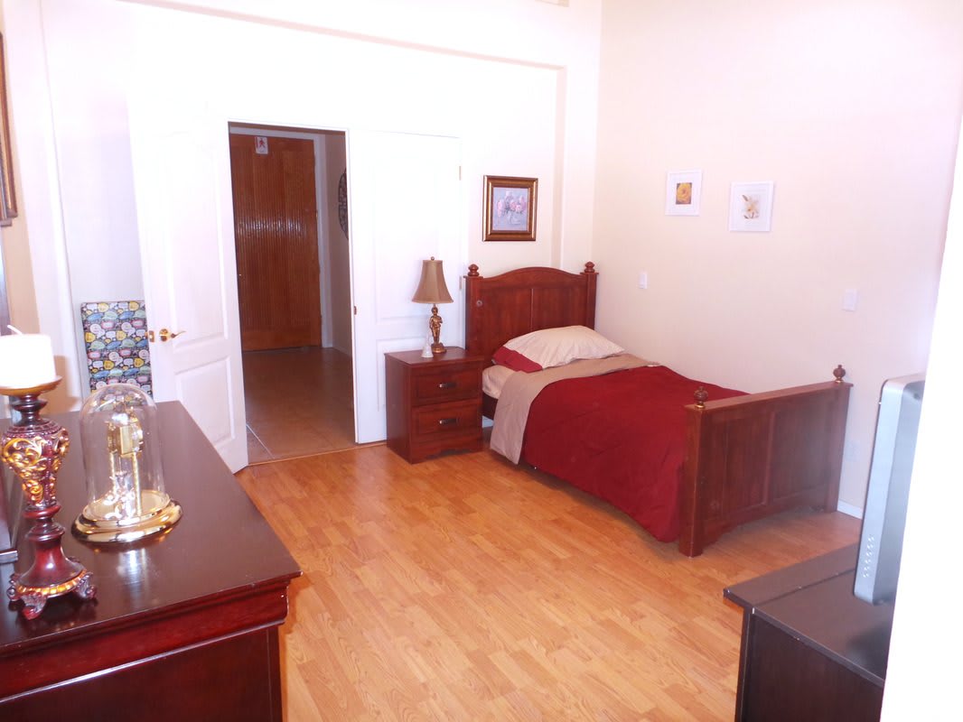A cozy bedroom featuring a single bed with wooden furniture and minimalist decor.