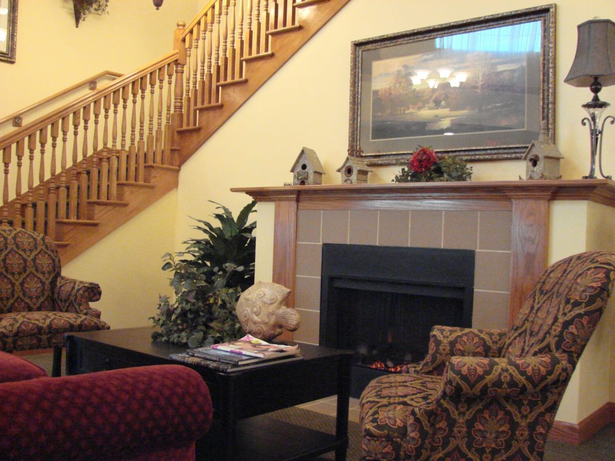 A cozy living room with a fireplace, elegant staircase, and comfortable seating.