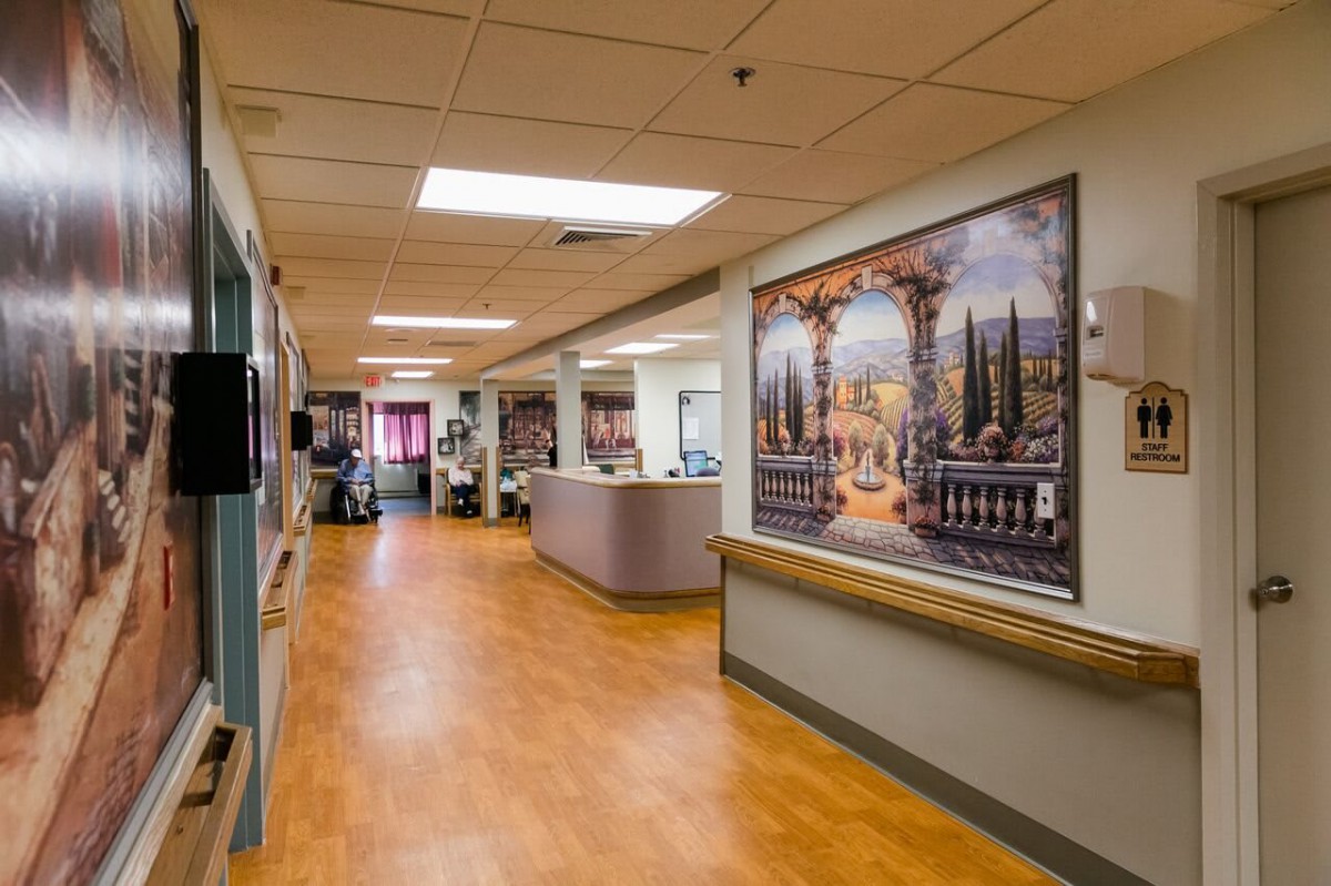 A hospital hallway featuring a large decorative painting on the wall.
