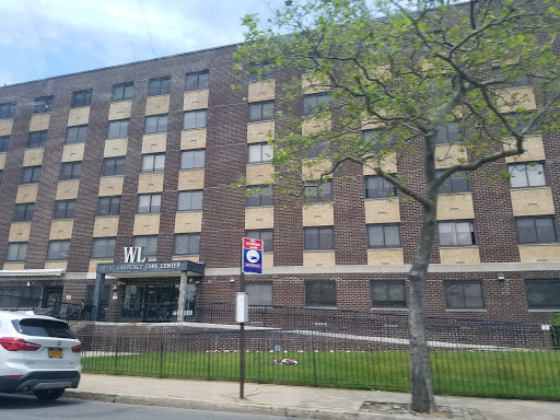 A multi-story brick building with a welcoming entrance and greenery in front.